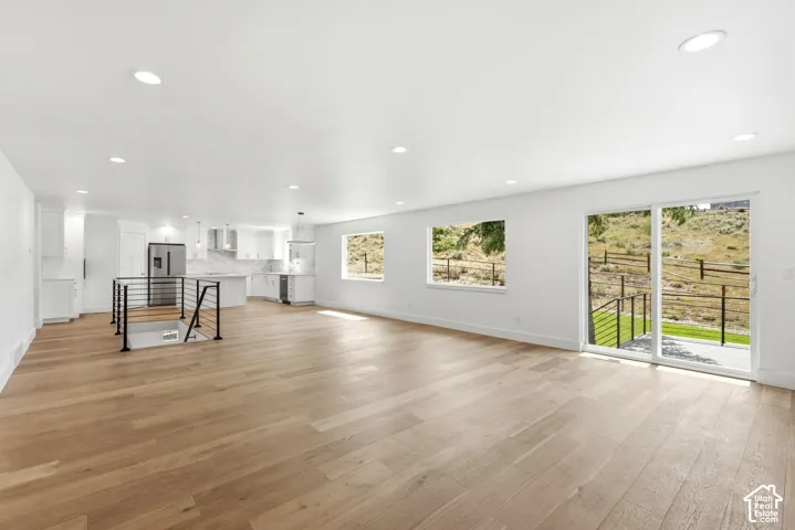 Open-concept living area with wood-finish flooring, recessed lighting, and white walls
