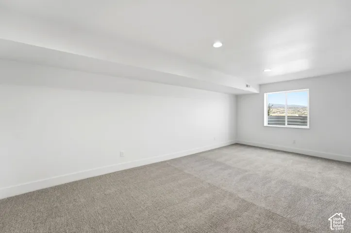 Recessed lighting, large window, mountain scenery, gray carpeting, and white walls