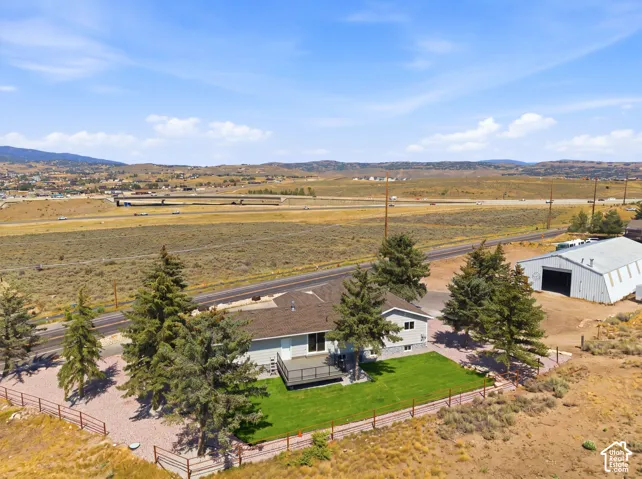 Single-story residence with a composite shingle roof, rear deck, and a fenced, manicured lawn