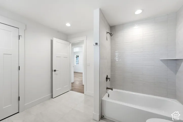 Bathroom featuring a built-in bathtub with tiled surround, a recessed shower niche, and recessed ceiling lighting