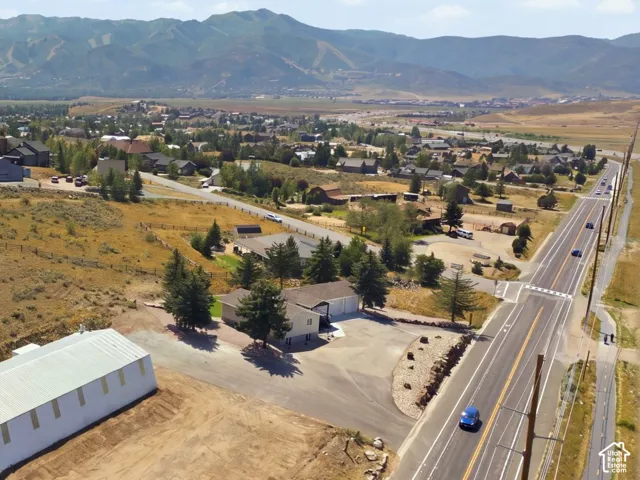 Expansive lot featuring a large white outbuilding, paved road frontage, and a mountainous backdrop