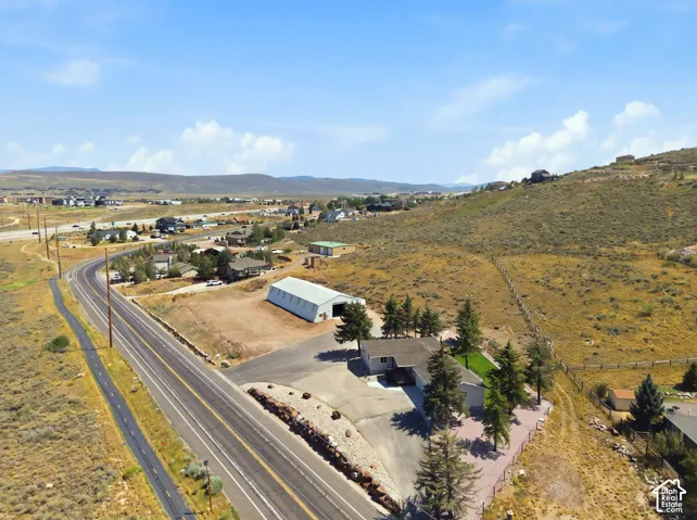 Expansive property featuring a single-story residence, separate outbuilding, paved driveway, and mature landscaping