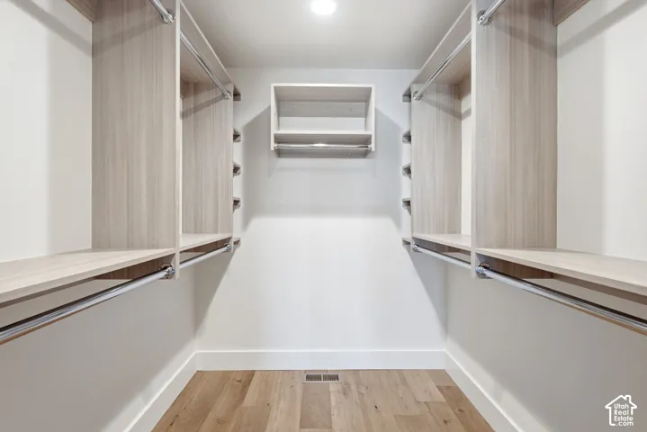 Custom closet organization system with blonde wood-finish shelving and chrome hanging rods