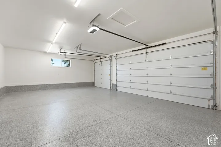 Spacious garage featuring a durable epoxy floor, white walls, and two overhead garage doors