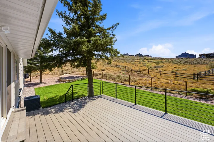 Spacious outdoor deck with composite decking, modern cable railing, and a manicured lawn