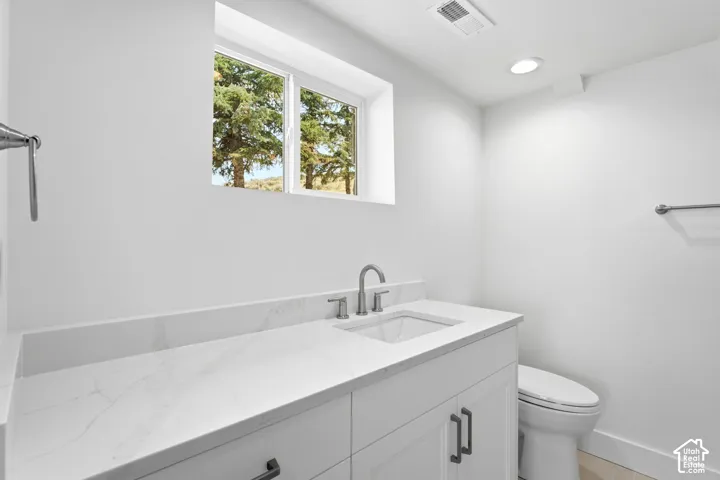 White vanity with dark hardware, undermount sink, and a stone-finish countertop