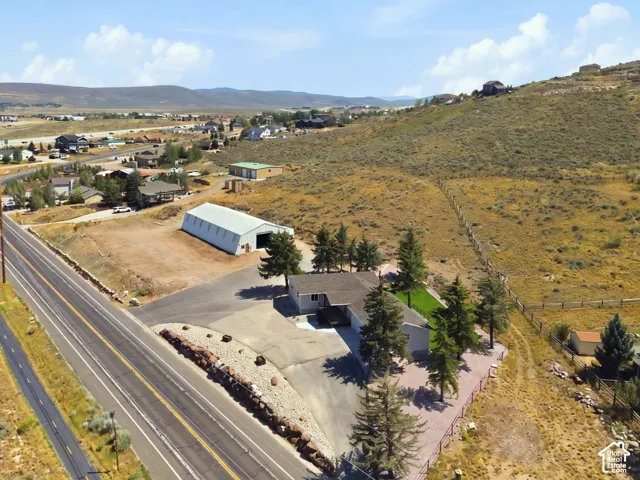 Expansive property featuring a single-story residence, separate outbuilding, paved driveway, and mature landscaping