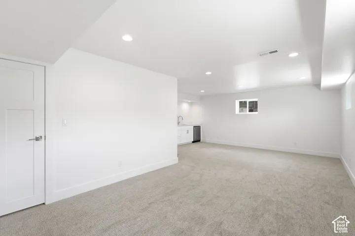 Recessed lighting, light-toned carpet flooring, white walls, built-in wet bar with white cabinetry, and a beverage refrigerator