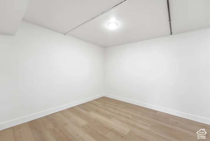Recessed ceiling lighting illuminates the space, featuring light wood-finish flooring and crisp white walls
