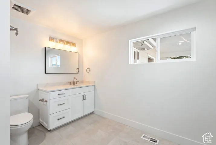 White vanity with a single basin, brushed nickel faucet, and a wall-mounted mirror