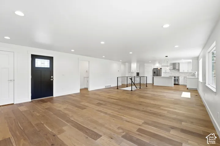 Expansive wood-finish flooring throughout, recessed lighting, and a modern kitchen with stainless steel appliances
