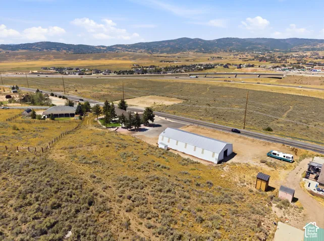 Expansive property featuring a large white outbuilding, paved roadways, and a natural landscape with distant mountainous terrain