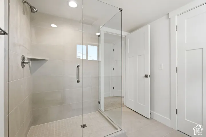 Glass-enclosed shower with a tiled surround, integrated shelf, and chrome fixtures