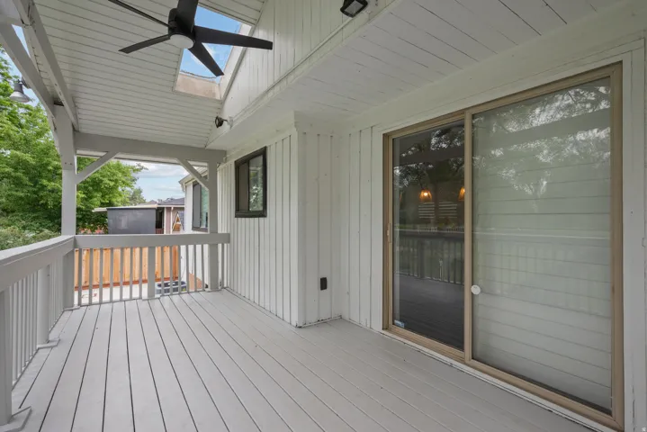 Covered deck with a skylight, ceiling fan, and sliding glass door