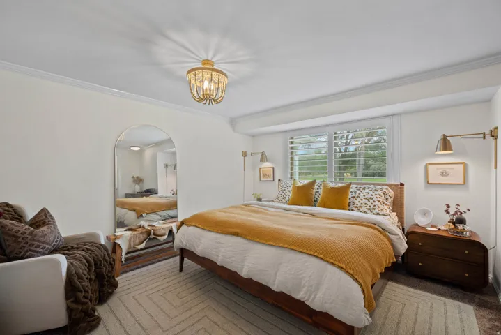 Arch-top mirror, wood-finish flooring, plantation shutters, wall-mounted sconces, and a decorative ceiling light fixture