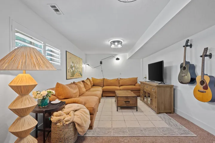 White walls with a contrasting ceiling beam, recessed lighting, and a window with plantation shutters
