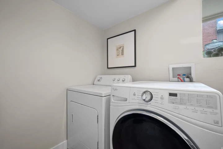 Laundry area with white appliances and a window