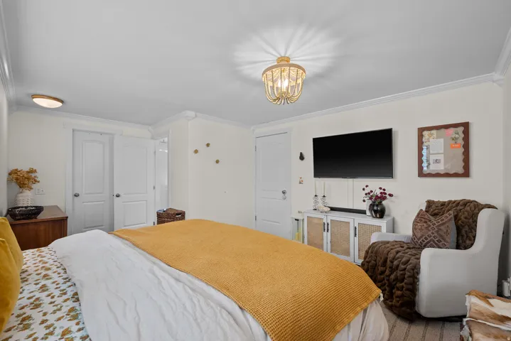 Wall-mounted television with a dedicated media console, two paneled closet doors, and a ceiling-mounted light fixture
