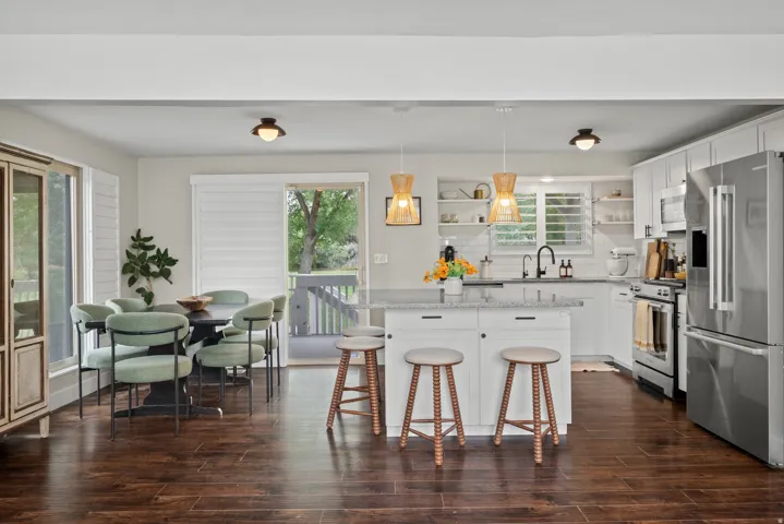 Spacious kitchen featuring white cabinetry, stainless steel appliances, a center island with seating, and wood-finish flooring