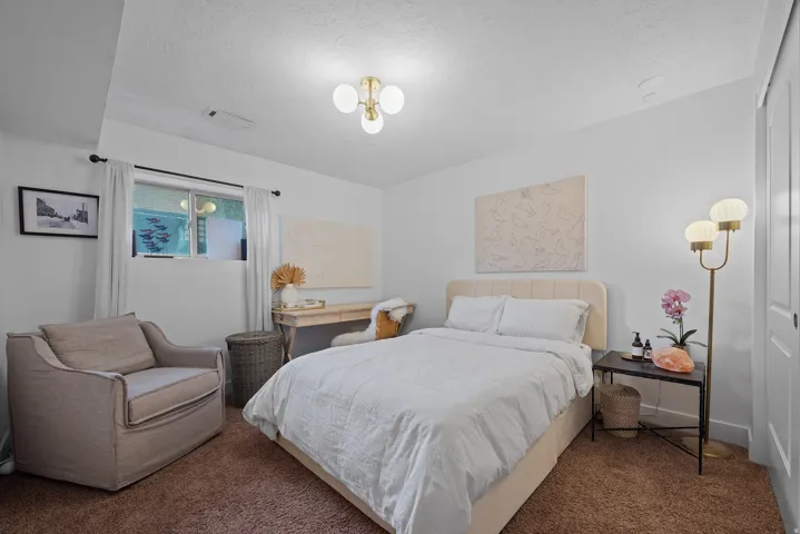 White painted walls with a window, brown carpeted flooring, and a gold-finish ceiling light fixture