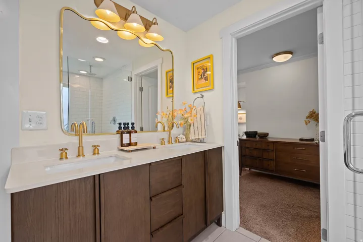 Dual vanity with white countertop, brass fixtures, and dark wood-finish cabinetry