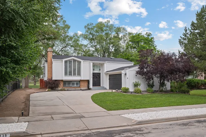 Split-level exterior with white siding, a prominent brick chimney, and a black front door with decorative glass