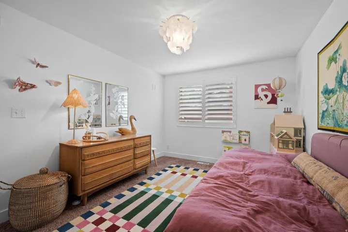 White walls with a textured ceiling light fixture, plantation shutters, and carpeted flooring