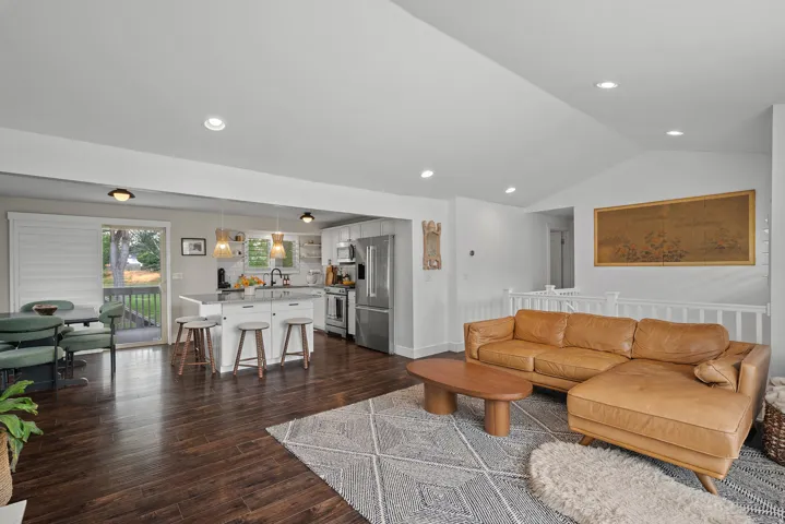 Open-concept living space featuring wood-finish flooring, recessed lighting, and a vaulted ceiling