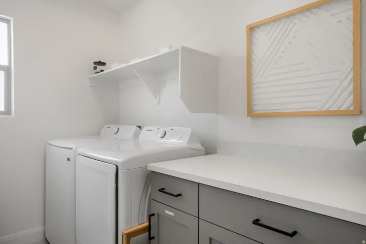 White cabinetry with a functional shelf, light-colored countertop, and a window providing natural illumination