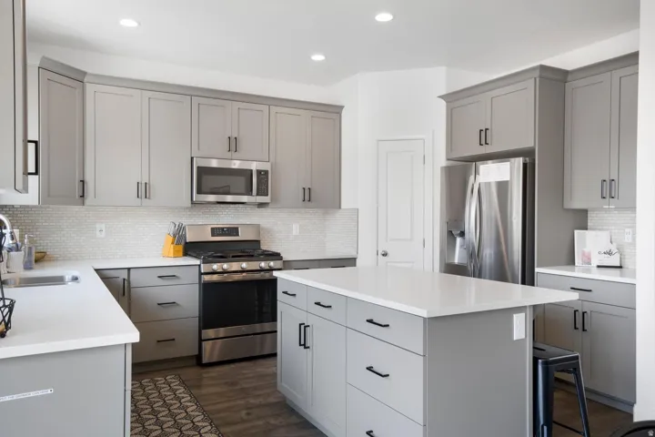 Kitchen featuring gray cabinetry, stainless steel appliances, a center island with a white countertop, recessed lighting, and wood-finish flooring