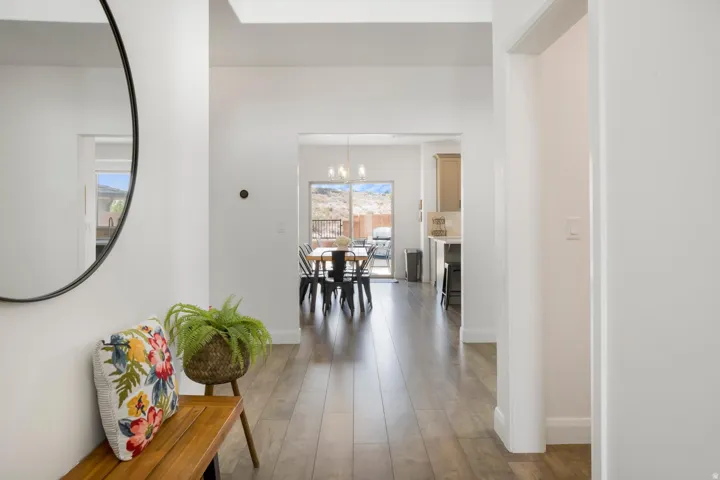 Wood-finish flooring throughout, white wall finishes, recessed lighting, and an open doorway leading to the kitchen and dining area