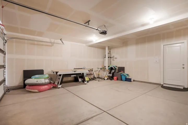 Spacious garage with concrete flooring, overhead lighting, and an automatic garage door opener