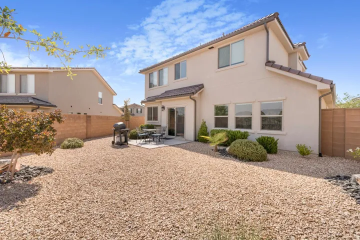 Stucco exterior with multiple windows, tile roof accents, and a ground-level patio