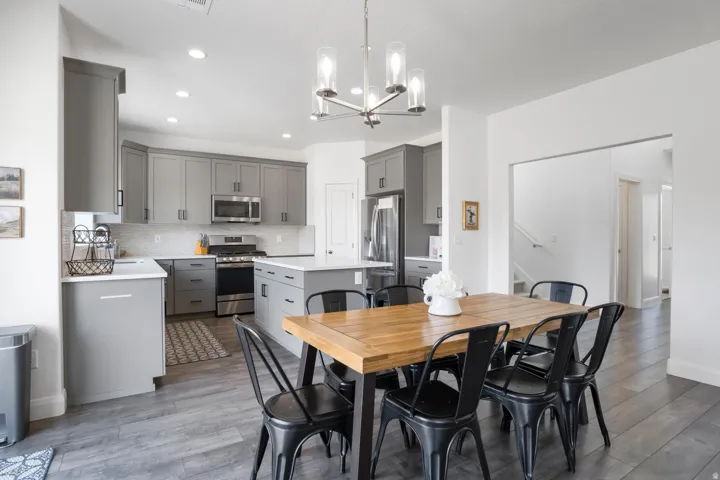 Modern kitchen featuring grey cabinetry, stainless steel appliances, a center island with a white countertop, and wood-finish flooring