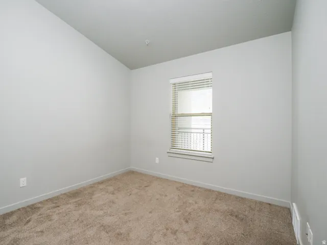 Neutral paint palette, textured carpet flooring, single window with blinds, overhead lighting fixture