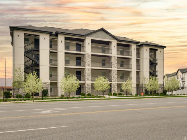 Multi-story building featuring a stucco and stone veneer exterior, dark-colored roof, and multiple balconies with dark railings