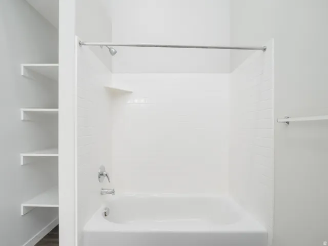 White tile shower surround with integrated shelving and chrome fixtures