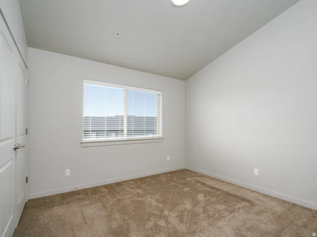 Neutral wall color, carpeted flooring, window with blinds, flush mount ceiling light, and white paneled doors