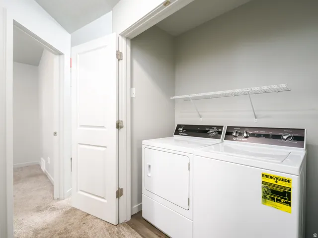 Laundry area featuring a wire shelf, white paneled doors, and wood-finish flooring