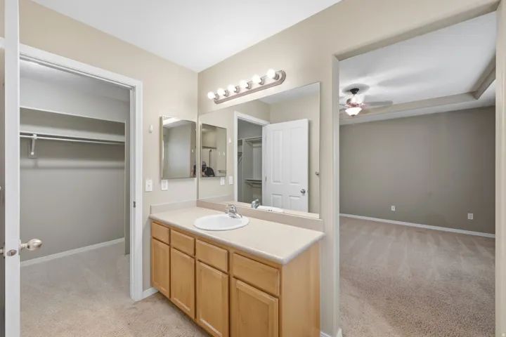 Vanity with integrated sink and wood-finish cabinetry, illuminated by a strip light