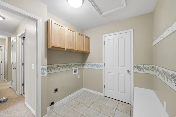 Utility space featuring tiled flooring, upper cabinetry, and a built-in bench