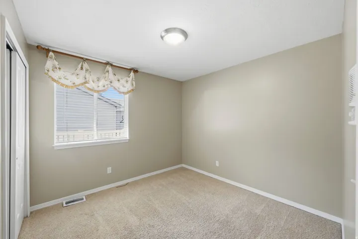 Soft beige wall paint, light neutral carpeting, and a window with horizontal blinds