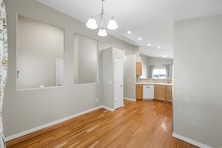Wood-finish flooring, recessed lighting, built-in wall niches, and a white dishwasher