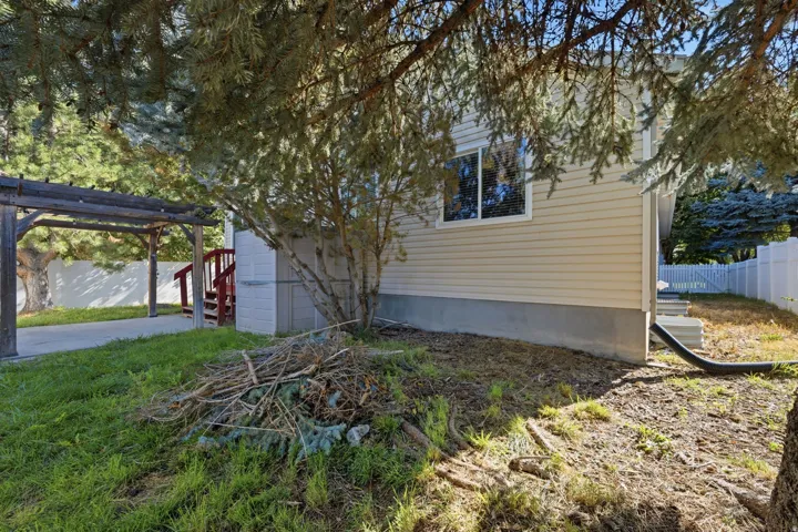 Vinyl siding exterior with a white perimeter fence and a concrete patio
