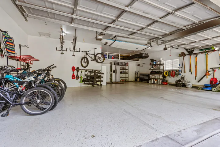 Spacious garage with epoxy-coated concrete flooring, extensive wall-mounted storage systems, overhead storage racks.