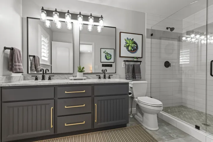 Spa-inspired primary bathroom featuring a dual-sink vanity with charcoal cabinetry, spacious shower, and marble countertop.