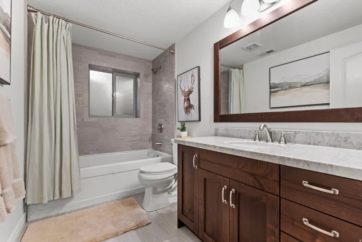 Bathroom with oversized bathtub, custom walnut cabinetry, and marble countertops