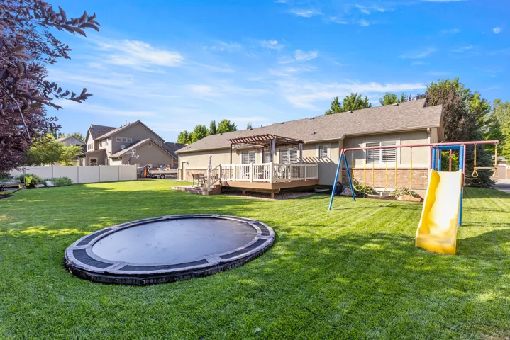 Backyard oasis featuring a manicured lawn, in-ground trampoline, and playset