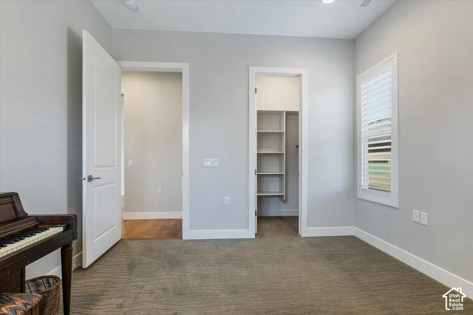 Neutral wall color, recessed lighting, window with plantation shutters, built-in closet shelving, and wood-finish flooring in an adjacent space