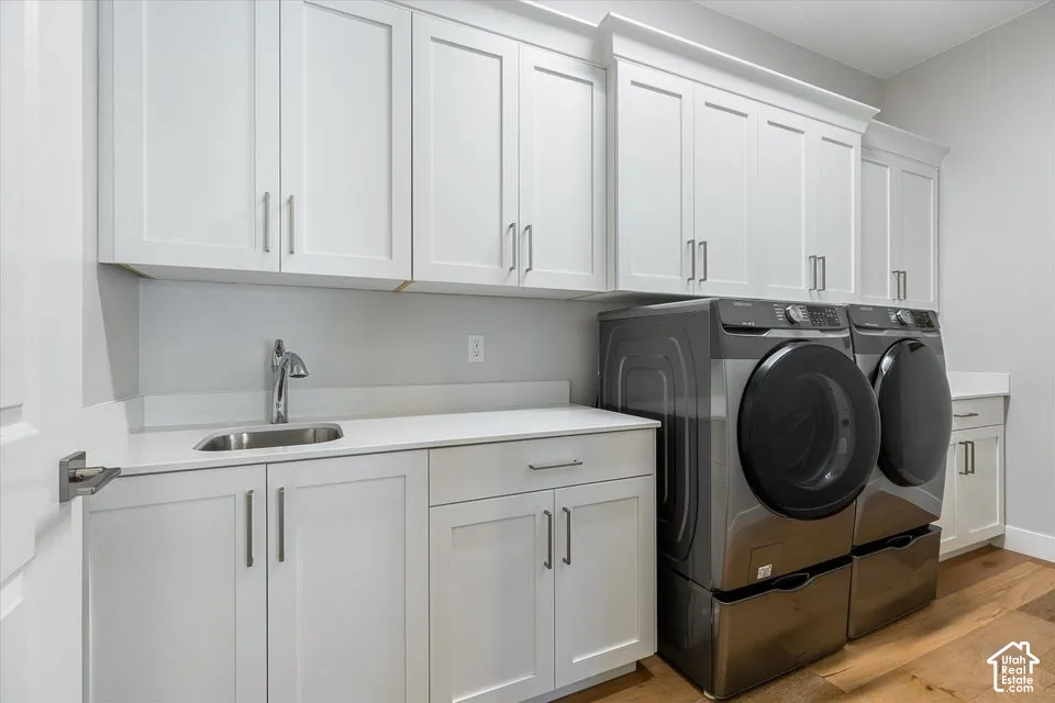 White shaker cabinetry, light-toned countertops, a utility sink with a chrome faucet, and wood-finish flooring